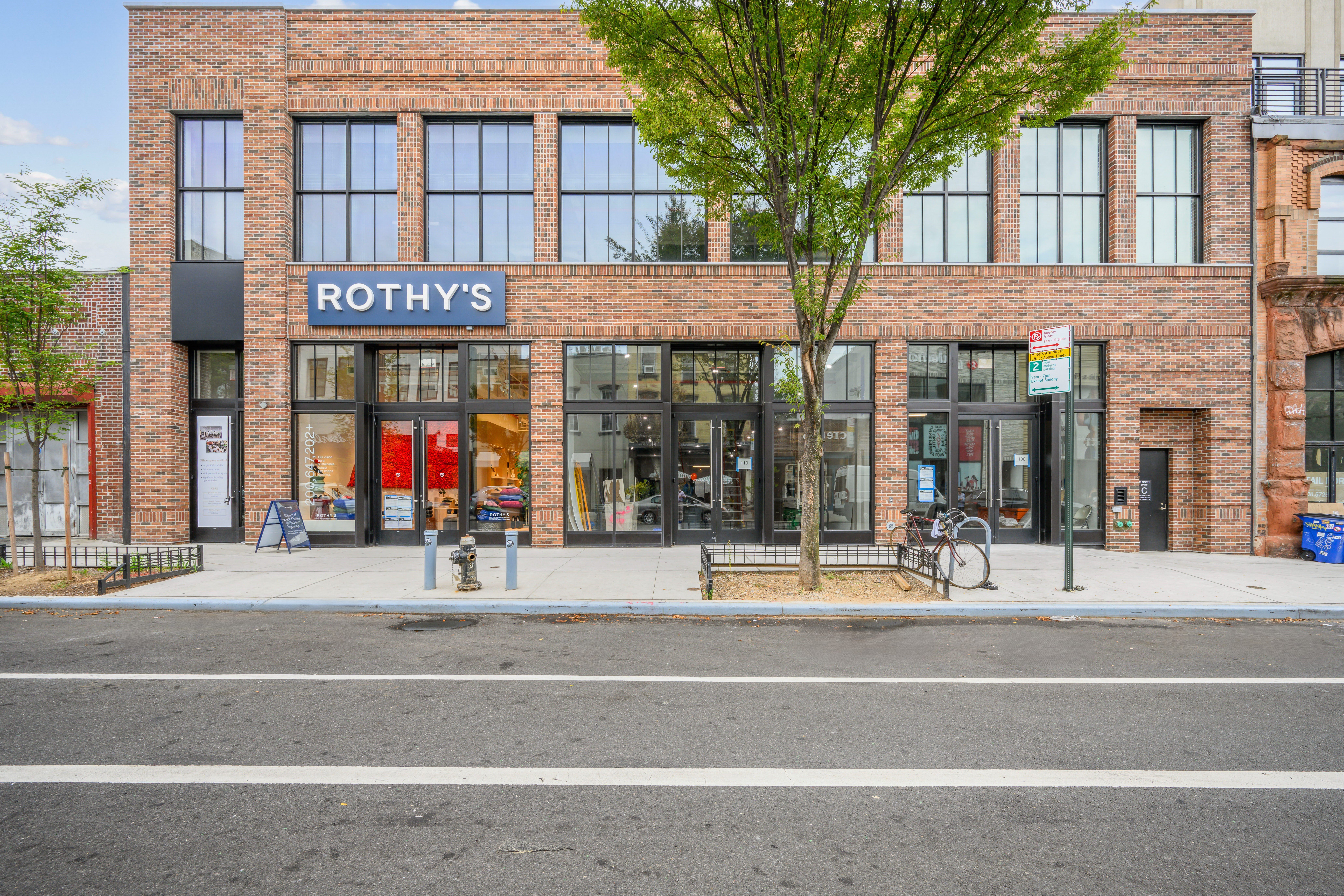two story brick building with rothy's store sign and one tree in front.